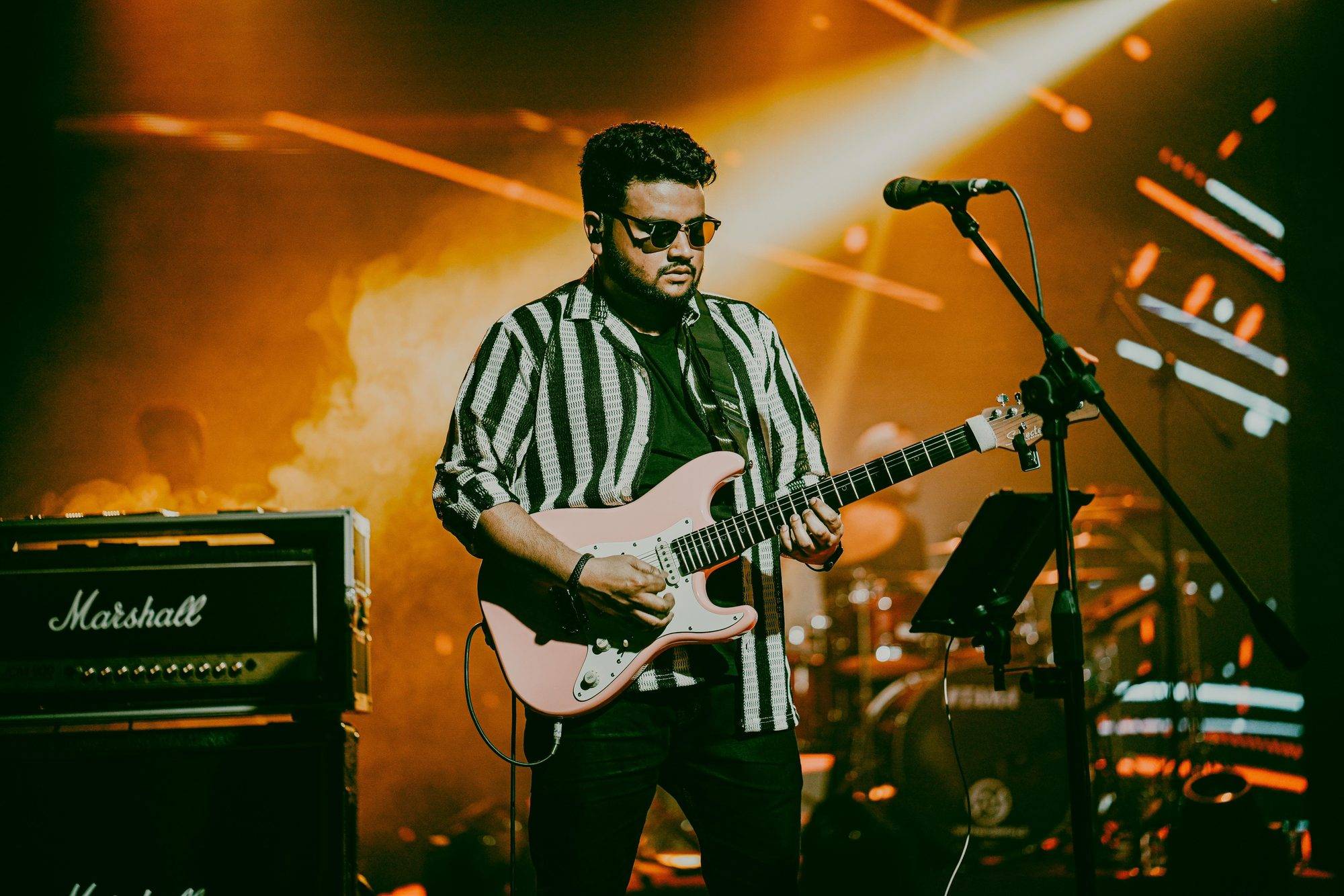 Elvis Mark Gabriel playing a pink Stratocaster on stage