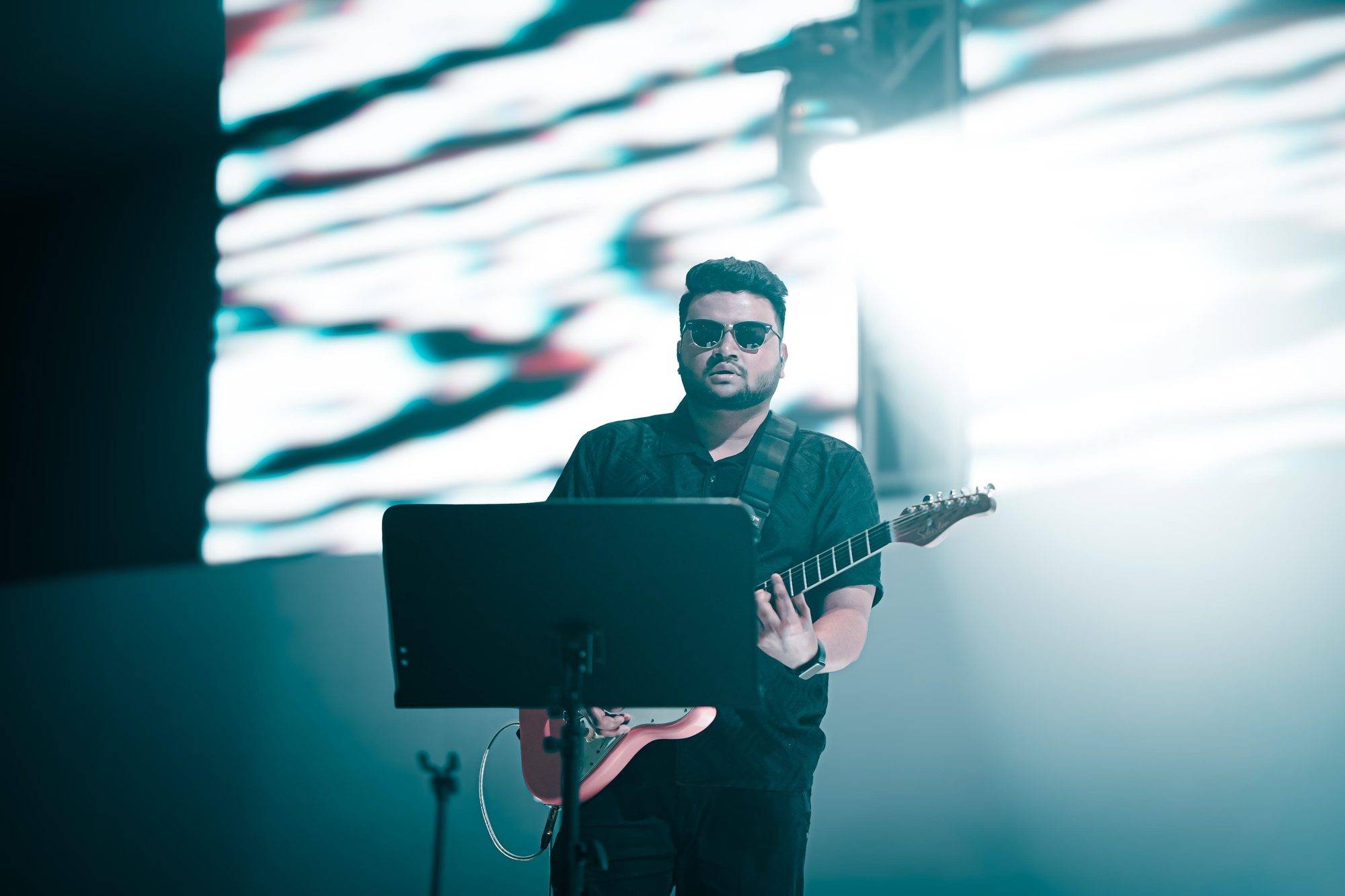 Elvis Mark Gabriel performing under teal stage lights