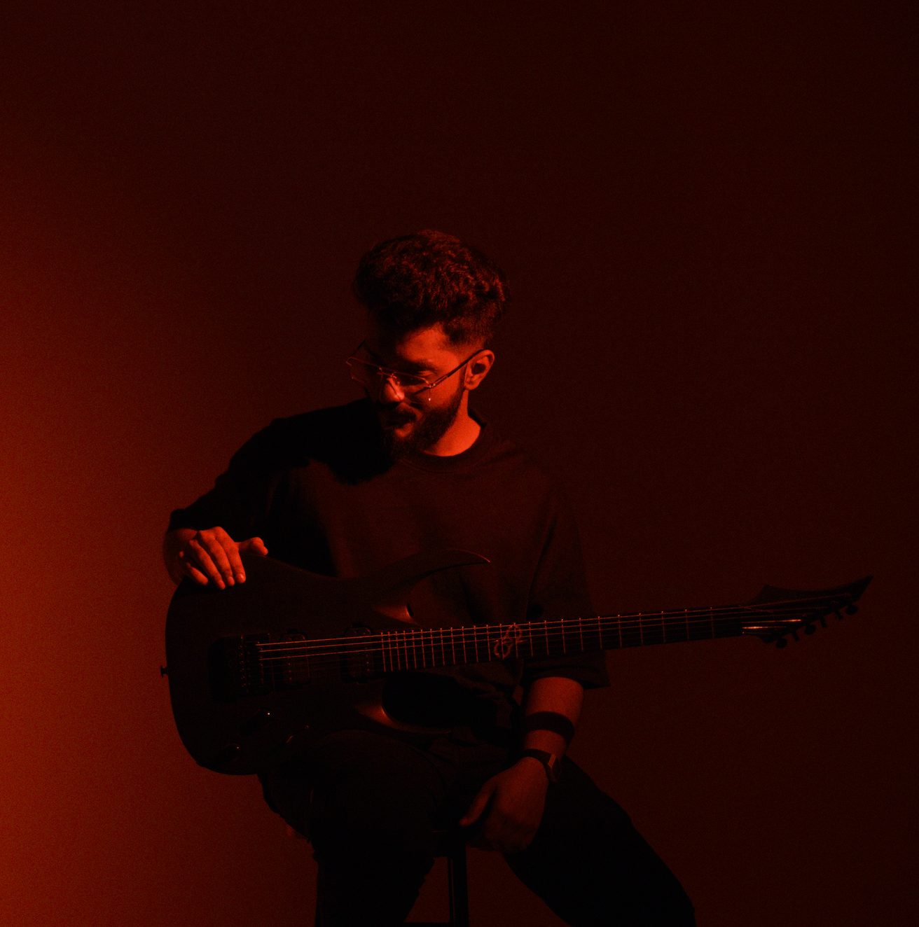 Ezekiel Bernard seated with his guitar in red light