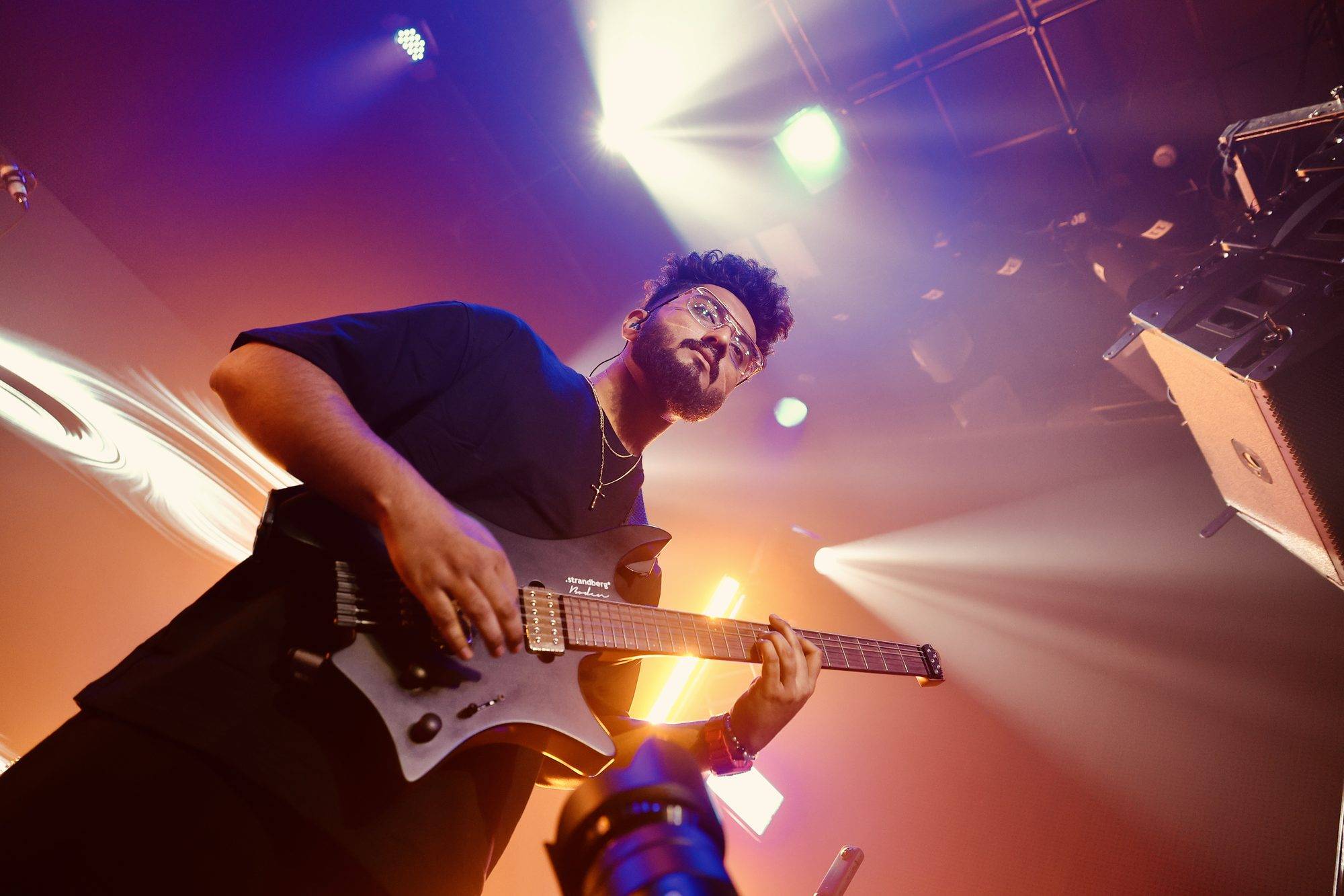 Ezekiel Bernard playing a Strandberg under purple stage lights