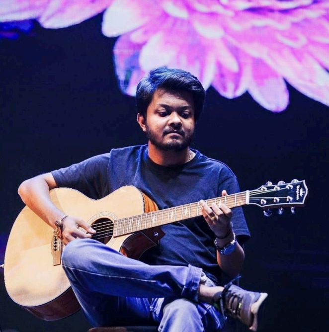 Abhishekh Prabhu performing on stage with floral backdrop