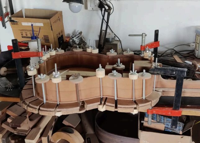 A guitar body clamped and drying in Rahul's workshop
