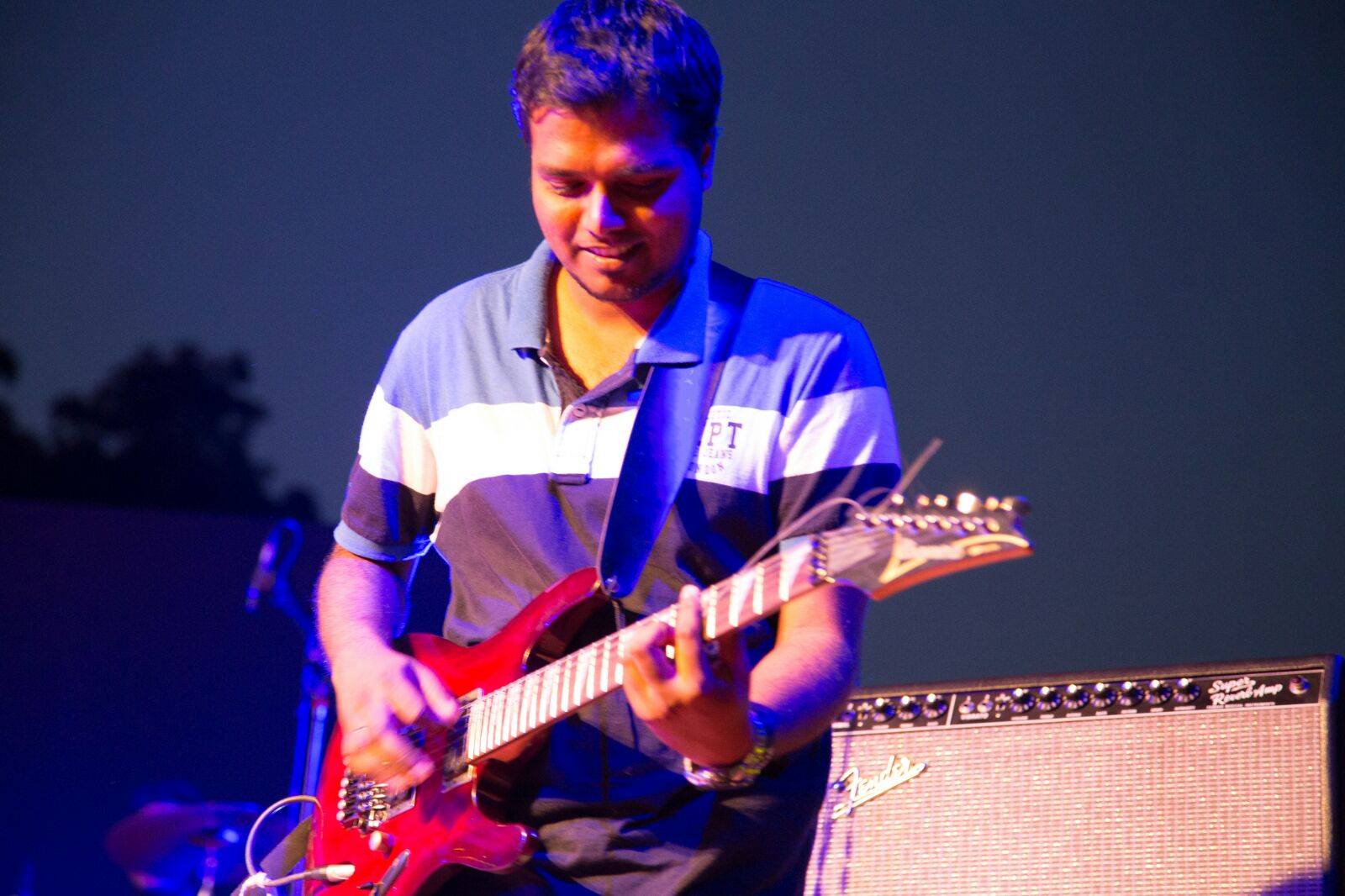 Stephen G Emmanuel playing a red electric guitar on stage